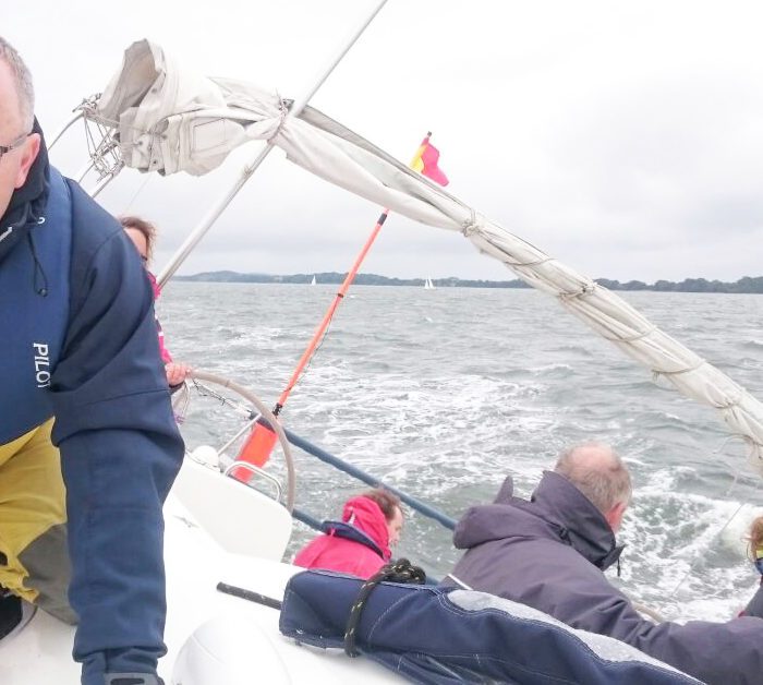 Regattacrew am Wind auf der Zielkreuz. Schräglage, alle mit Rettungswesten. Segeltörn Ostsee, Nebensaison.